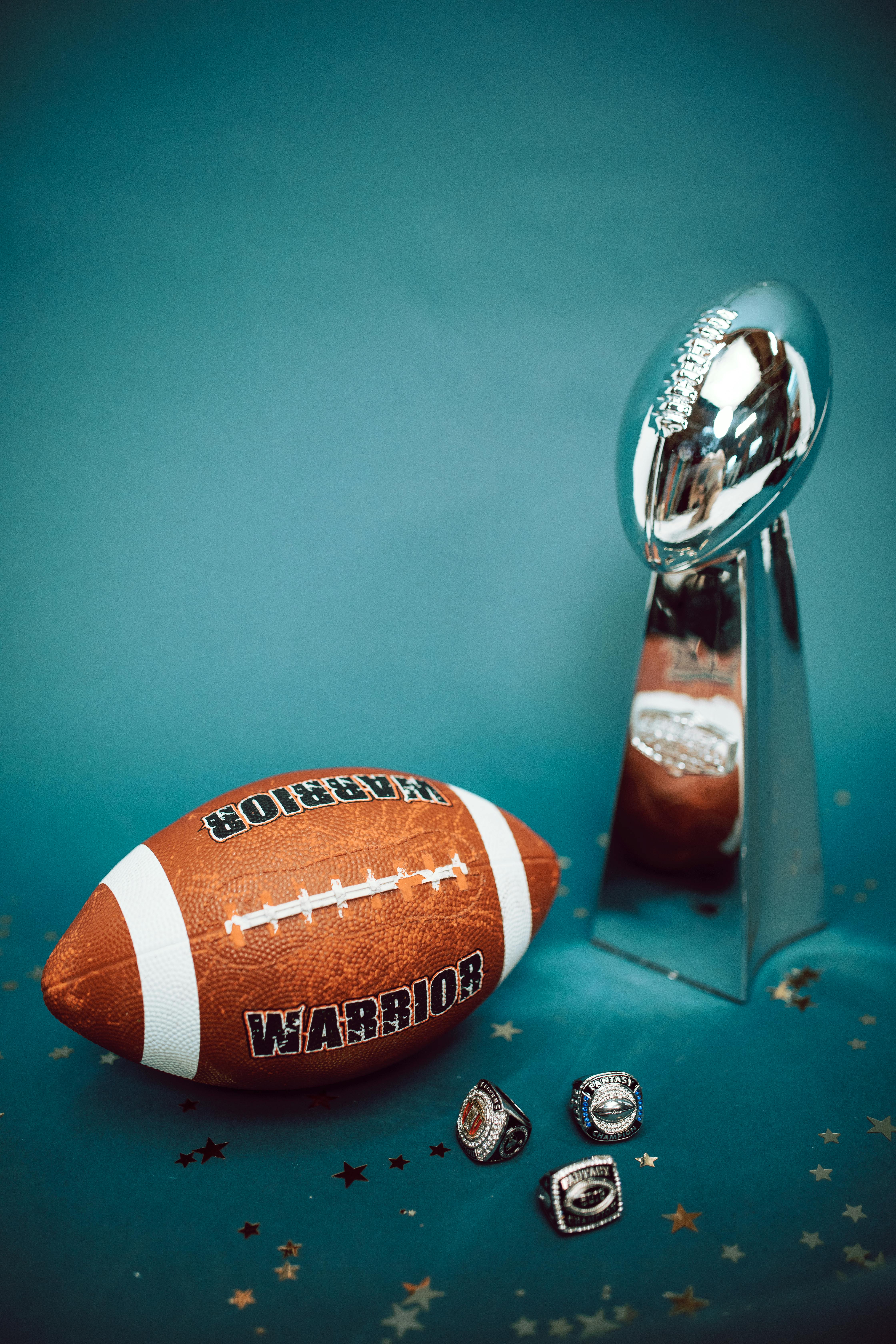 Super Bowl trophy and football on a teal background